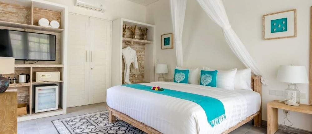 Bright, inviting hotel room at Kardia Resort Gili Trawangan with a large bed and teal accents.
