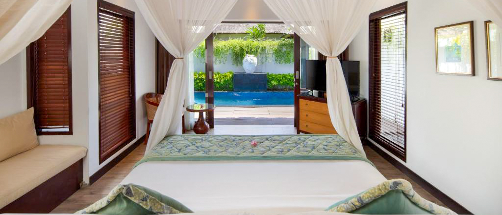 Luxurious private pool villa bedroom in Nusa Lembongan, opening to a tranquil outdoor pool.