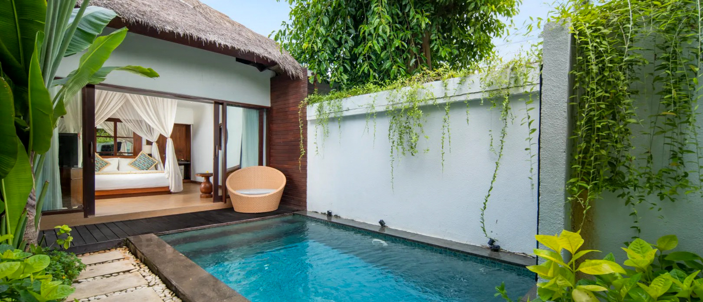 Luxurious private pool villa in Nusa Lembongan with a canopy bed, modern chair, and lush tropical plants.