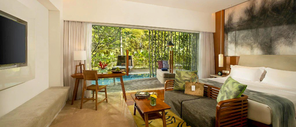Elegant resort room with a king bed and private pool, opening to tropical gardens in Sanur, Bali.