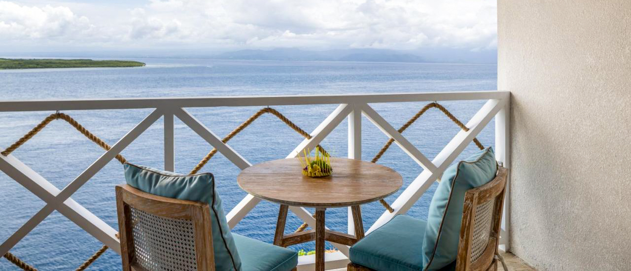 Luxurious private balcony with a table and chairs overlooking the vast blue ocean in Nusa Penida.