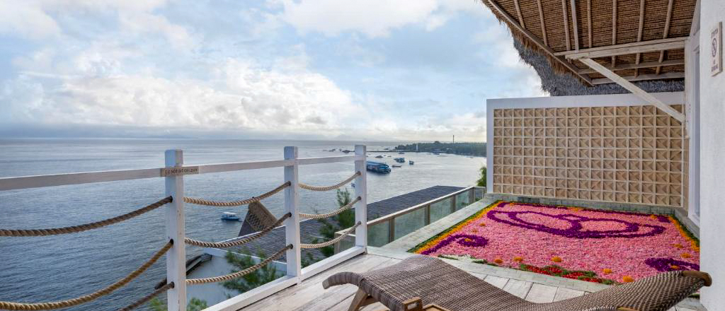 Balcony with a lounge chair, flower petal art, and stunning ocean views in Nusa Penida.