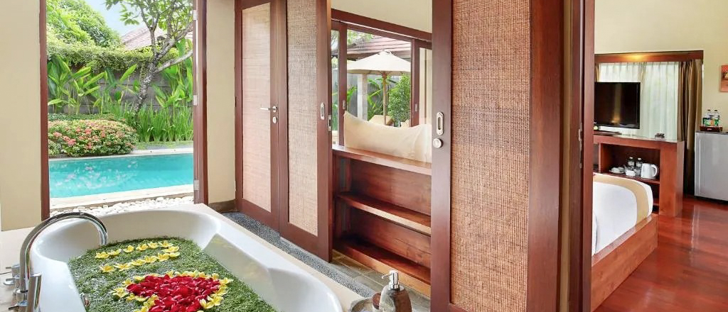 Romantic flower-filled bathtub in a luxurious Seminyak villa, with a private pool and bedroom.