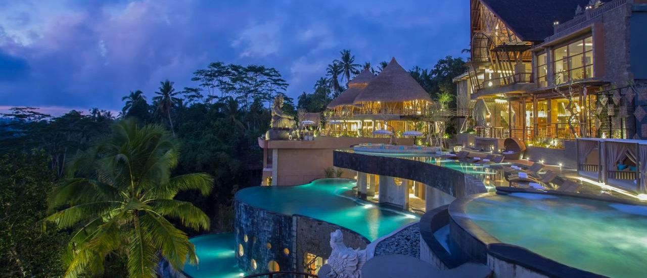 Luxurious Kayon Jungle Resort in Ubud, Bali, at dusk, with multiple illuminated pools overlooking the jungle.