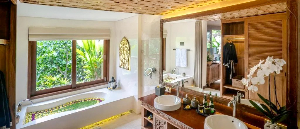 Luxurious bathroom in Ubud, Bali, featuring a flower-filled bathtub, double vanity, and lush jungle views.