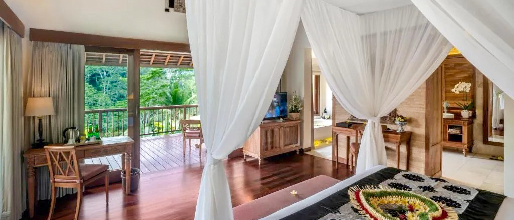 Inviting resort room in Ubud, Bali, with a comfortable bed and a private balcony facing the jungle.