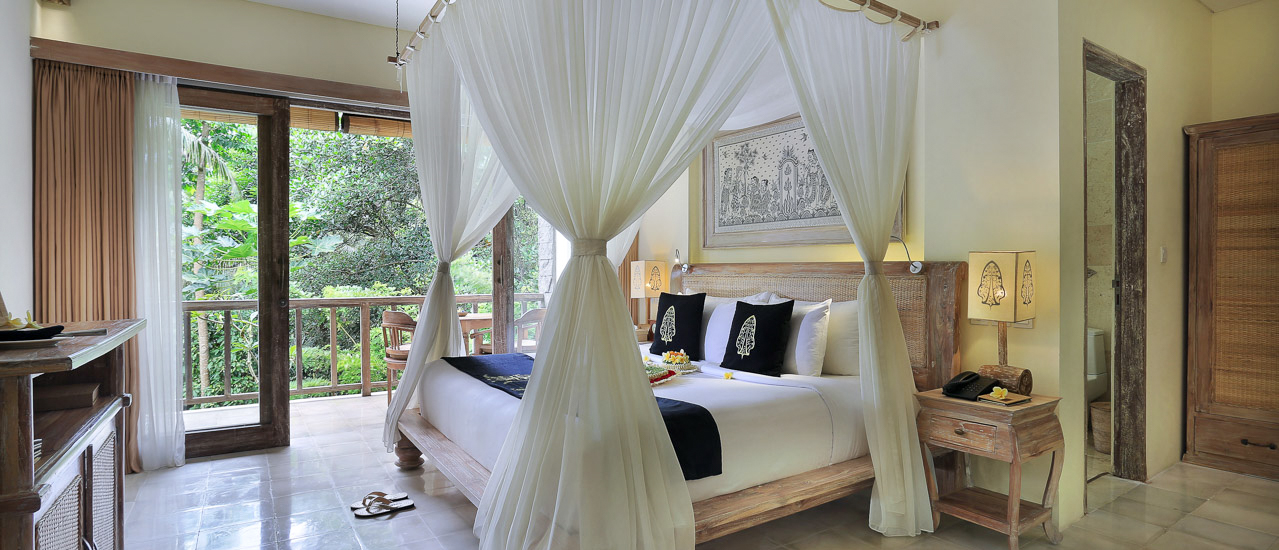 Elegant resort room in Ubud, Bali, featuring a canopy bed and a balcony with jungle views.