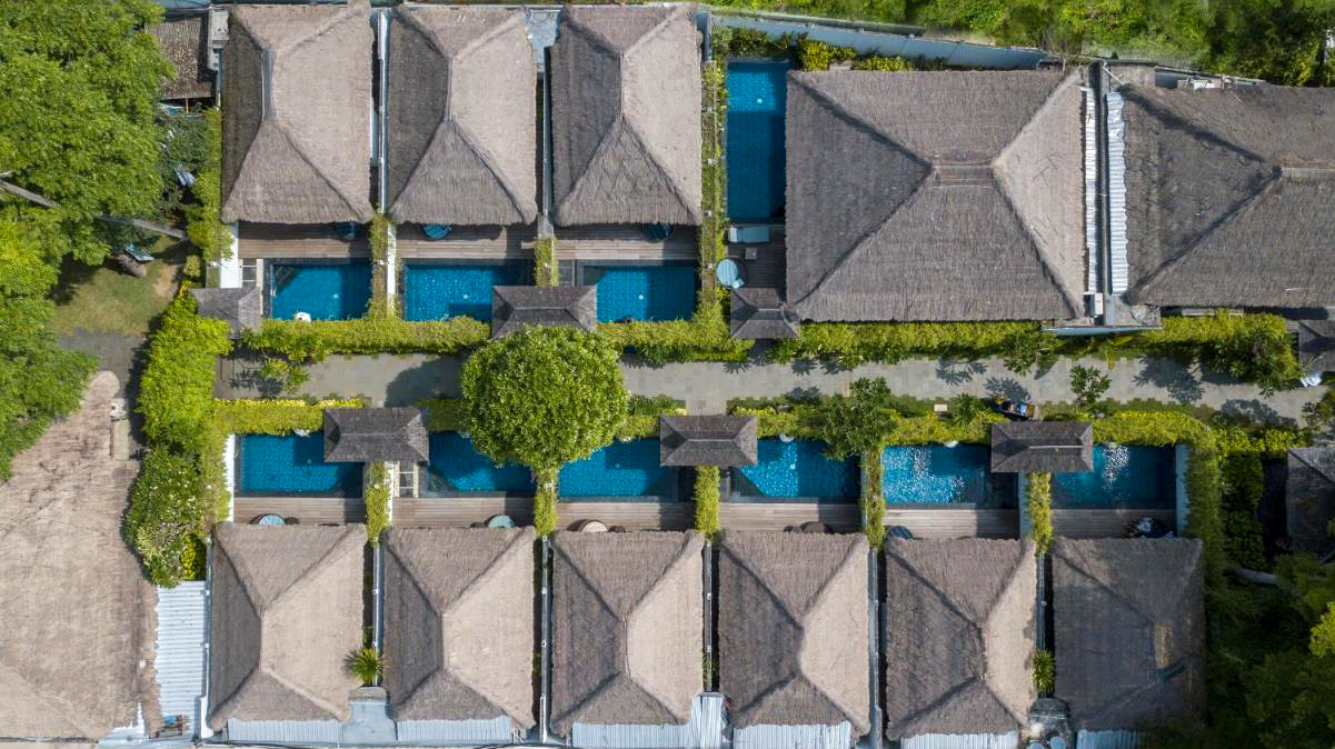 Aerial view of Lembongan Beach Club &amp; Resort, featuring thatched-roof villas, private pools, and lush gardens.