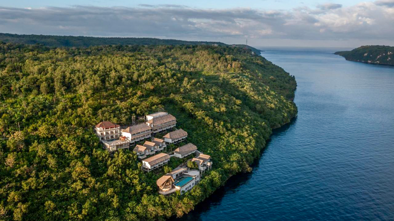 A beautiful resort nestled on a lush green cliff overlooking the calm blue ocean in Nusa Penida.