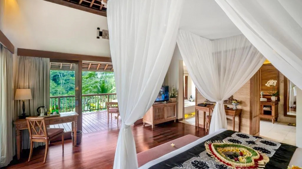 Luxurious bedroom with a four-poster bed and a balcony overlooking a lush jungle in Ubud, Bali.