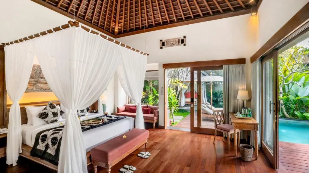 Elegant bedroom with a four-poster bed, traditional Balinese roof, and private pool at an Ubud resort.