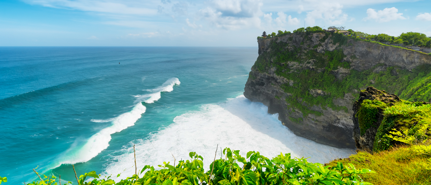 Majestic Uluwatu Temple perched on lush green cliffs overlooking the vast turquoise ocean in Bali.