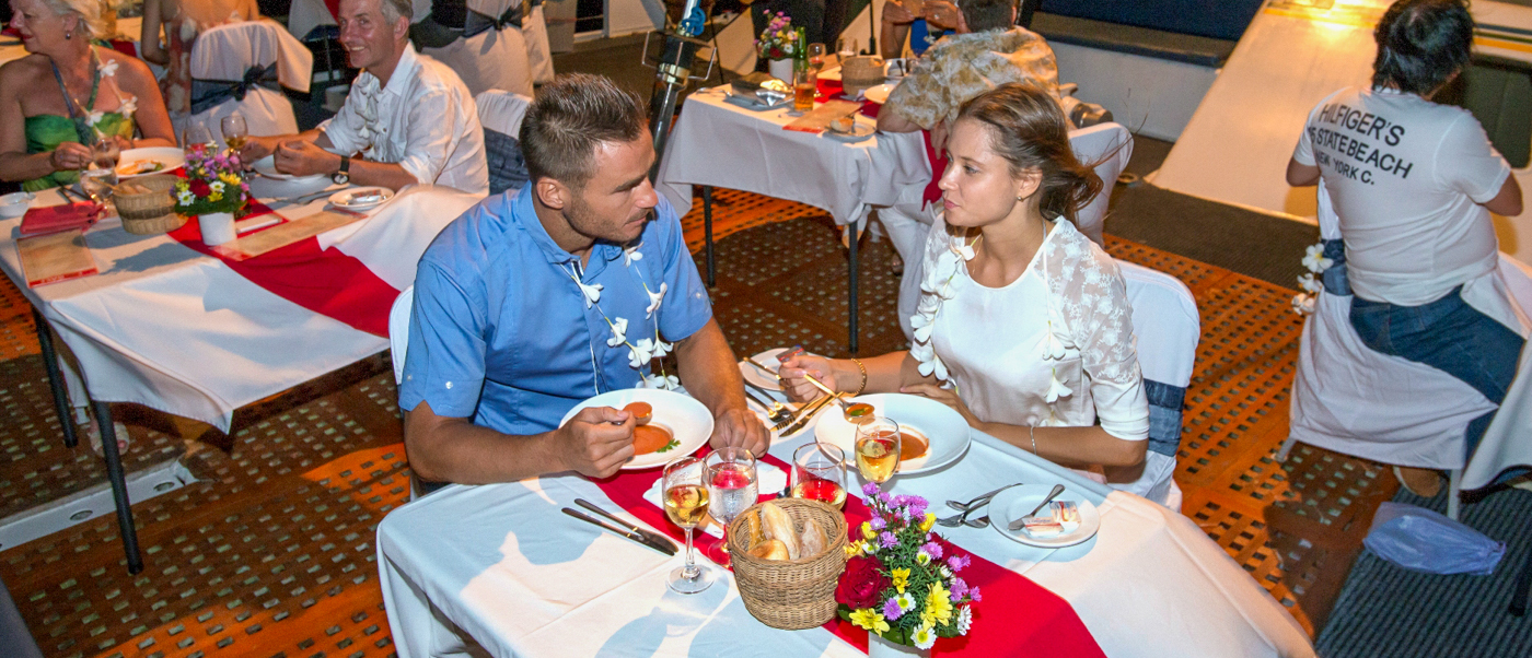 A couple enjoys a romantic dinner cruise in Bali, sharing a meal and conversation.