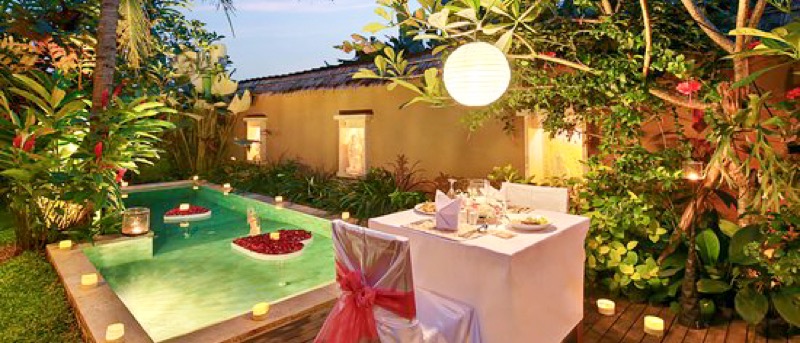 Romantic candlelit dinner for two by a private pool with floating rose petals in Bali.