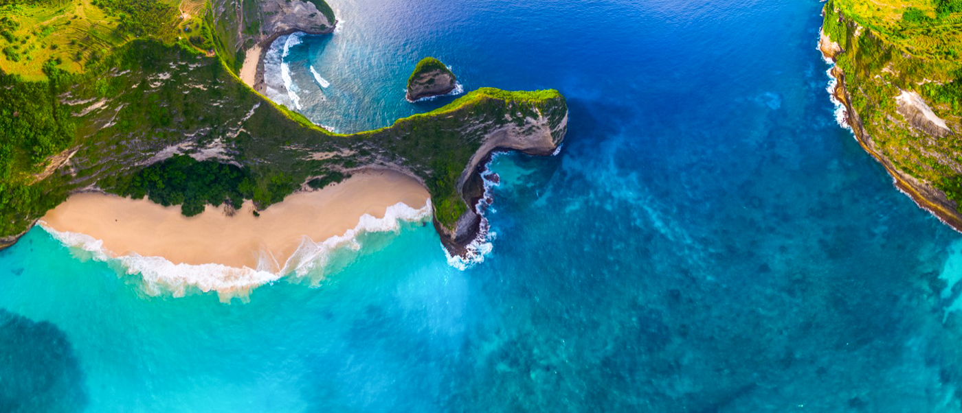 Aerial view of Kelingking Beach, Nusa Penida, with its iconic T-Rex shaped cliff and turquoise waters.