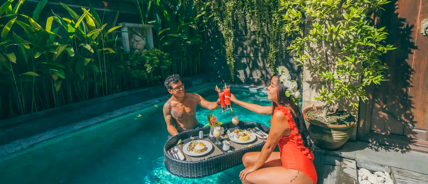 A couple enjoying a romantic floating breakfast in a private pool villa in Seminyak, Bali.