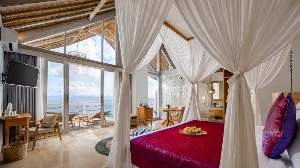 Elegant resort bedroom with a canopy bed, private balcony, and breathtaking ocean views in Bali.