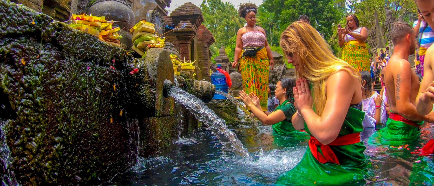 Tourists participate in a traditional water blessing ceremony at Tirta Empul Temple in Bali.