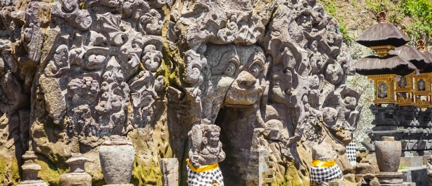 Intricate stone carvings of a mythical face at the entrance of Goa Gajah temple in Bali.