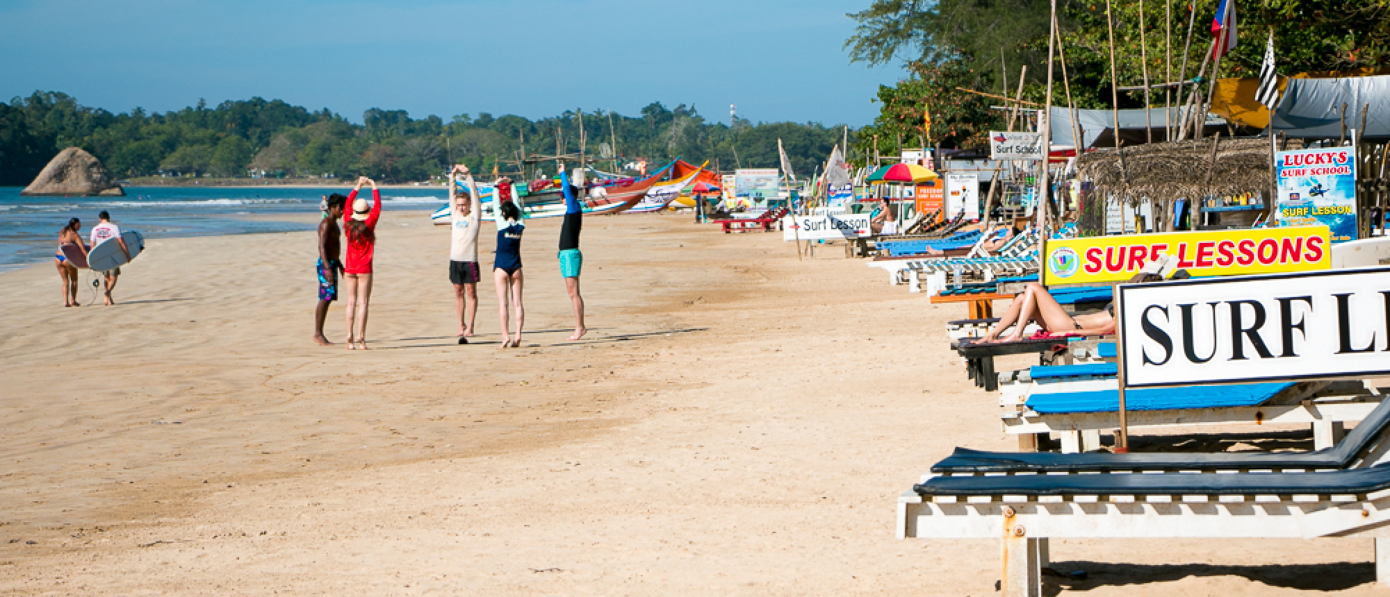 Tourists warm up for surf lessons on the sunny sandy beach in Weligama, Sri Lanka.