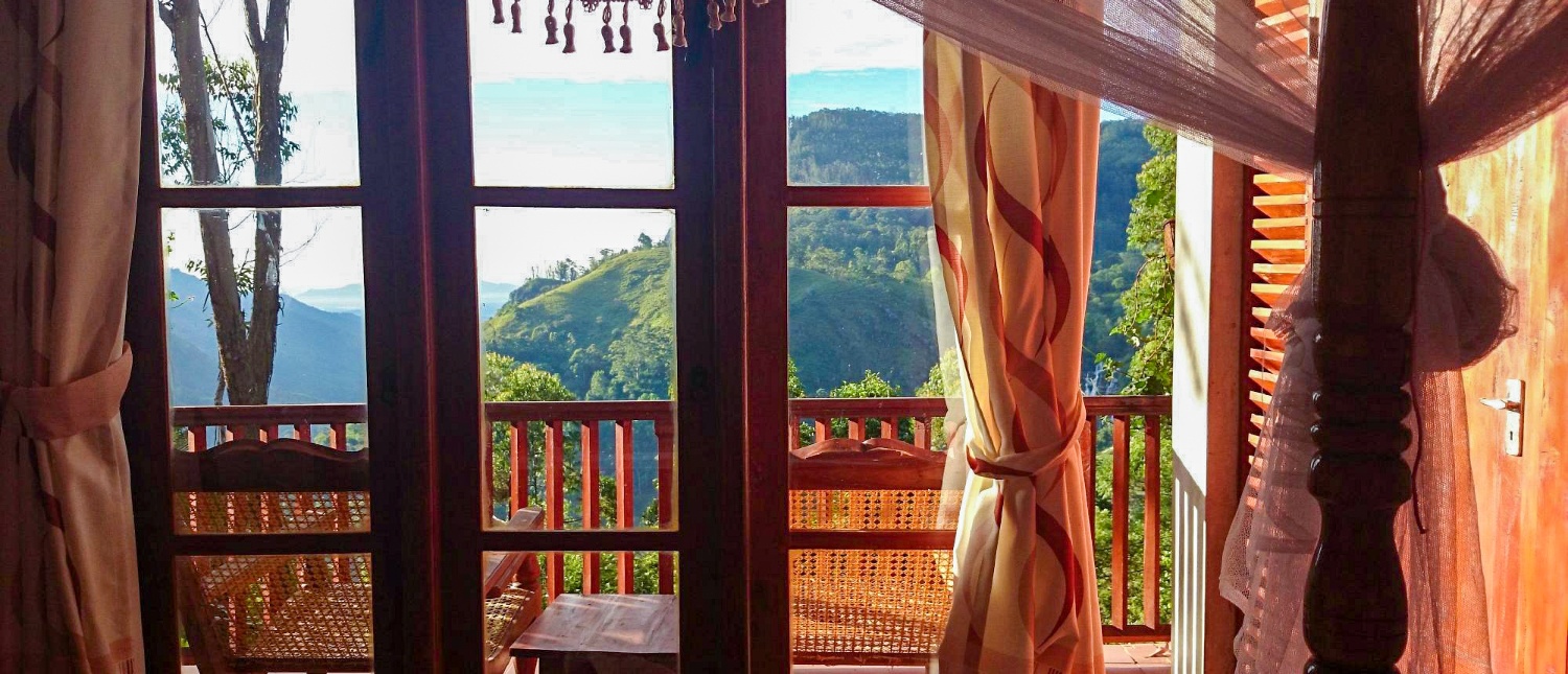 A serene view from a hotel room balcony overlooking lush green mountains in Ella, Sri Lanka.