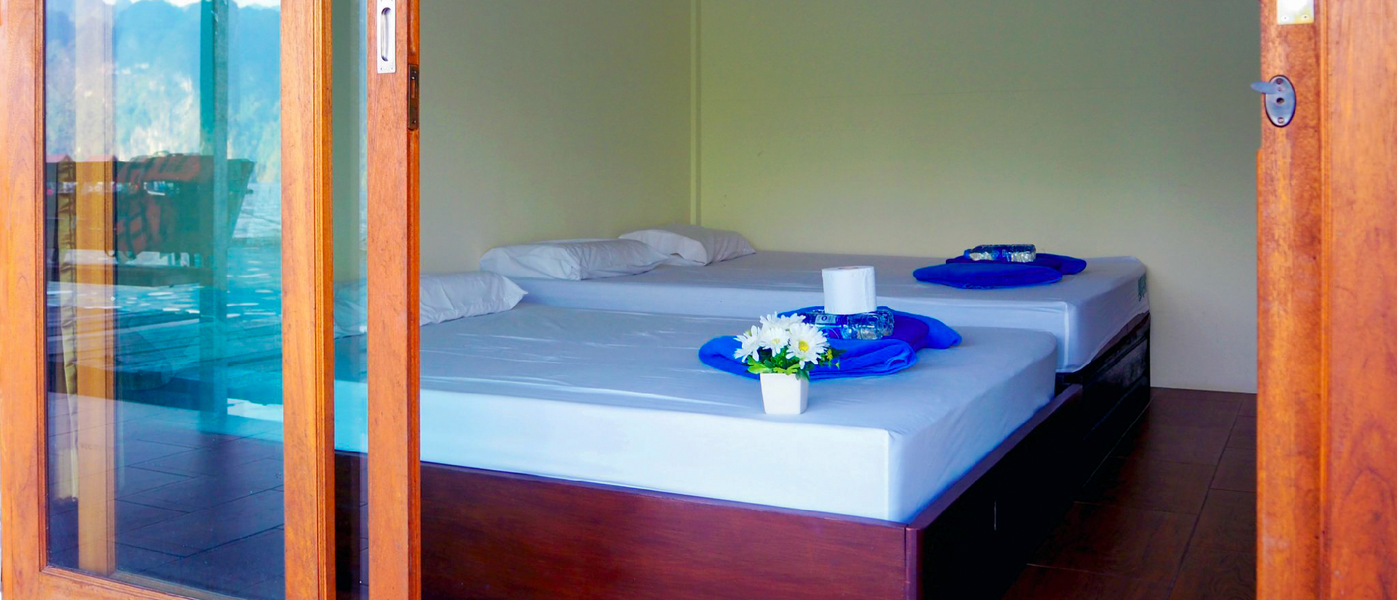 A cozy twin room in a floating bungalow with two beds and blue towels, Khao Sok National Park.