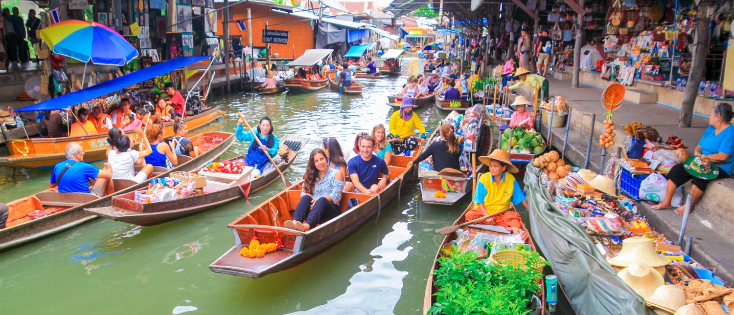 Tourists and vendors in boats at the vibrant Amphawa Floating Market in Thailand.