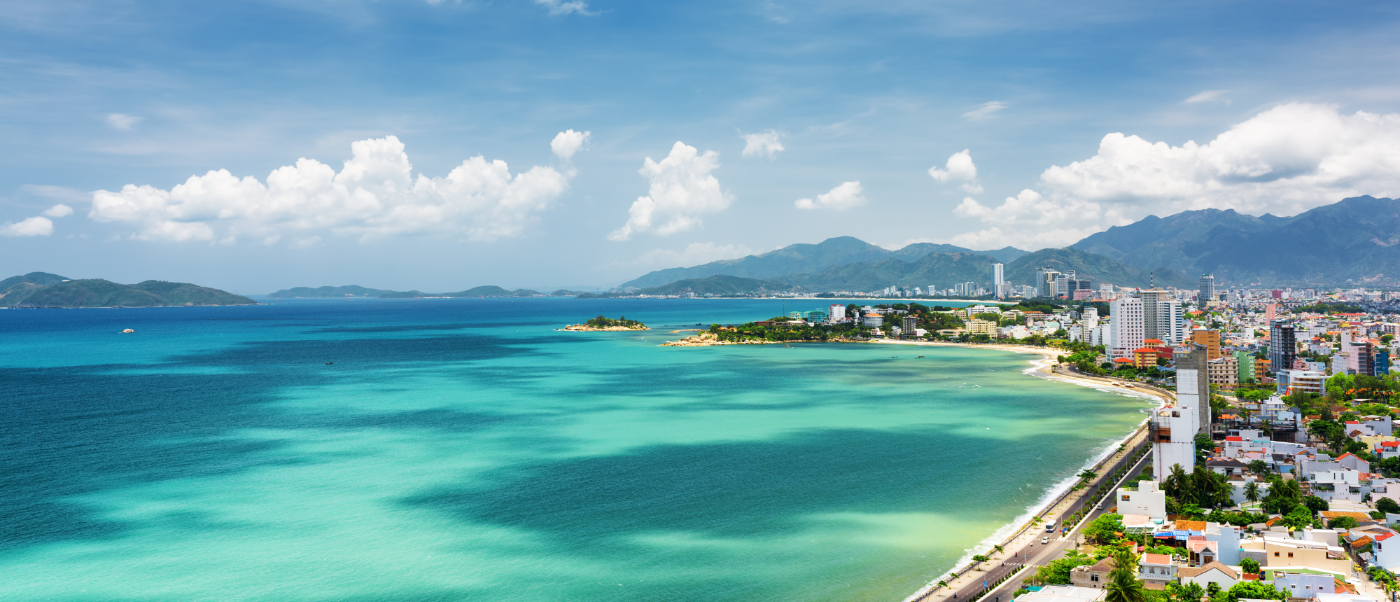 Aerial view of Nha Trang's vibrant coastal city with clear turquoise waters and distant mountains.