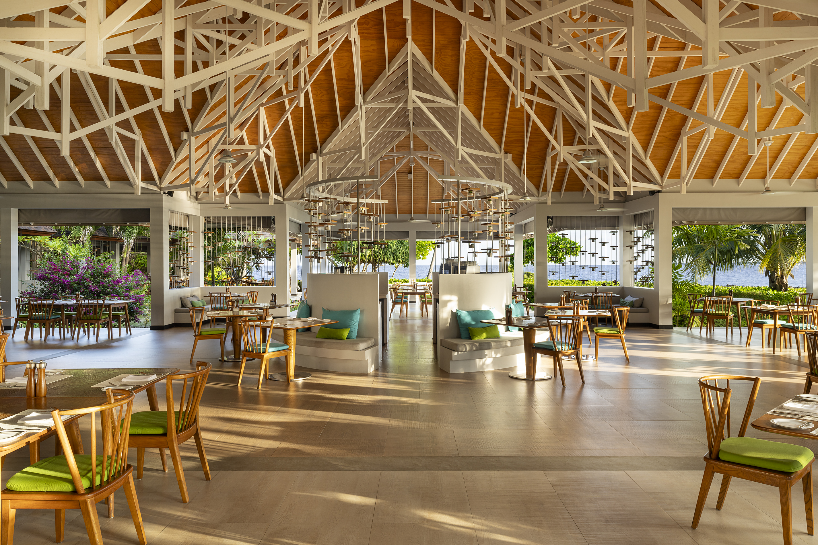 Bright, airy dining room at Dhigali Resort Maldives, featuring a high ceiling and ocean views.