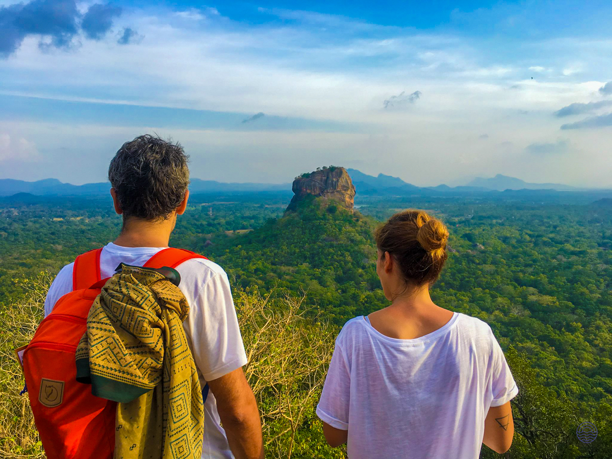 A couple admires the majestic Sigiriya rock fortress rising above the lush green landscape of Sri Lanka.