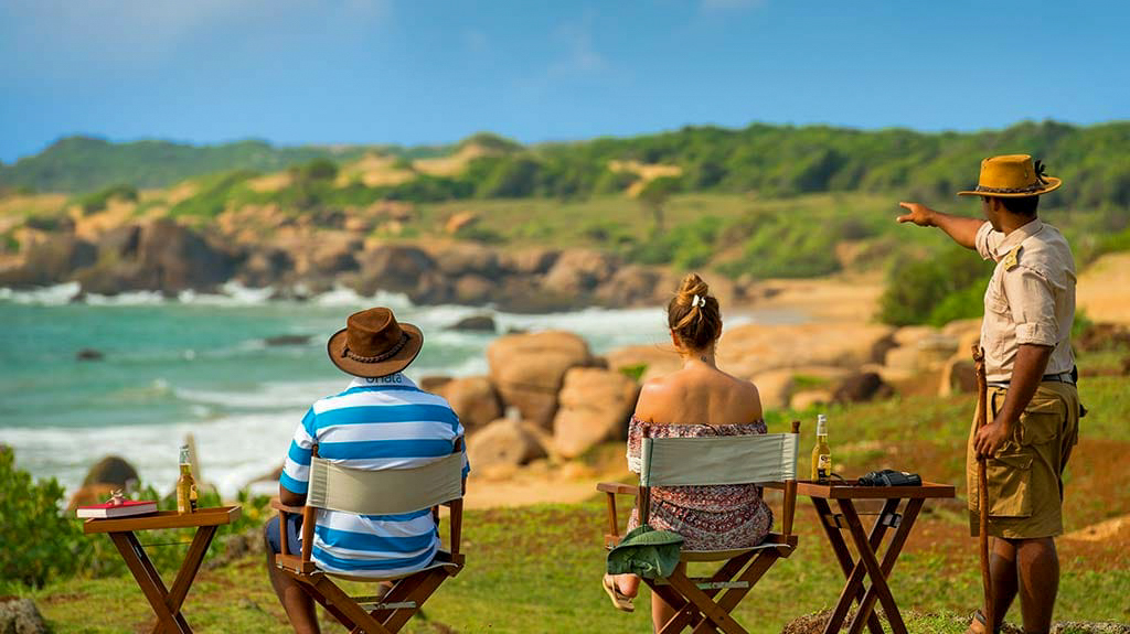 Tour guide points out sights to a couple enjoying the scenic rocky coast of Sri Lanka.