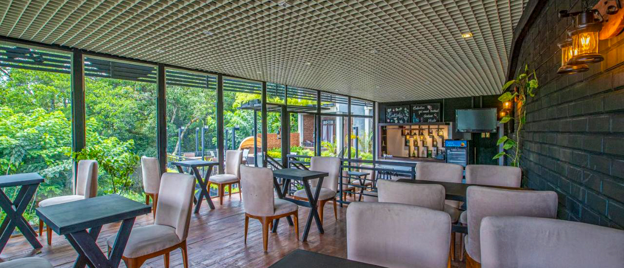 A bright, modern restaurant in Ella with comfortable seating and large windows overlooking lush green trees.
