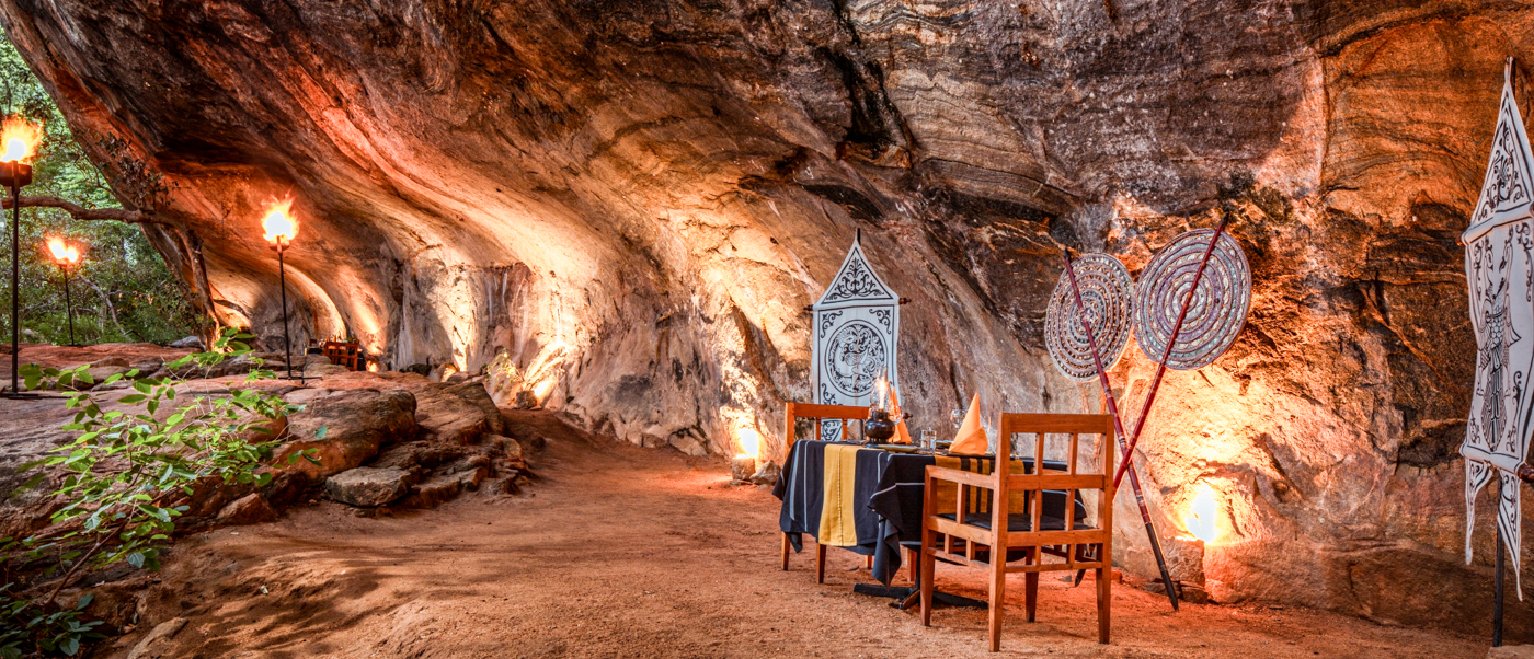 Romantic private dinner table for two inside a beautifully lit natural cave in Sigiriya, Sri Lanka.