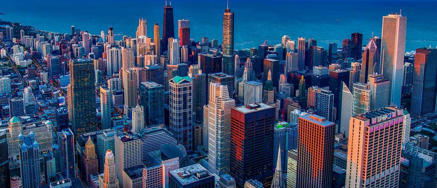 Aerial view of a sprawling modern city skyline with countless tall buildings under a clear blue sky.