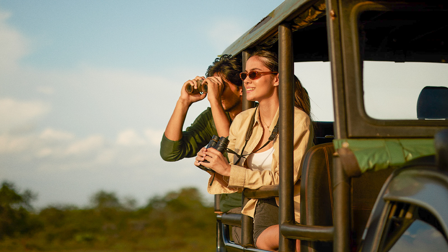 Happy couple on a safari jeep in Udawalawe National Park, looking for elephants and other wildlife.
