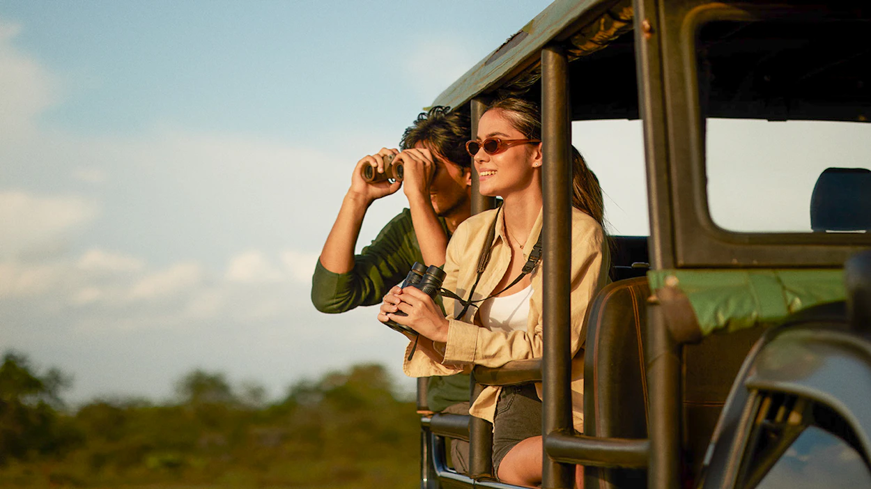 Happy couple on a safari jeep in Udawalawe National Park, looking for elephants and other wildlife.