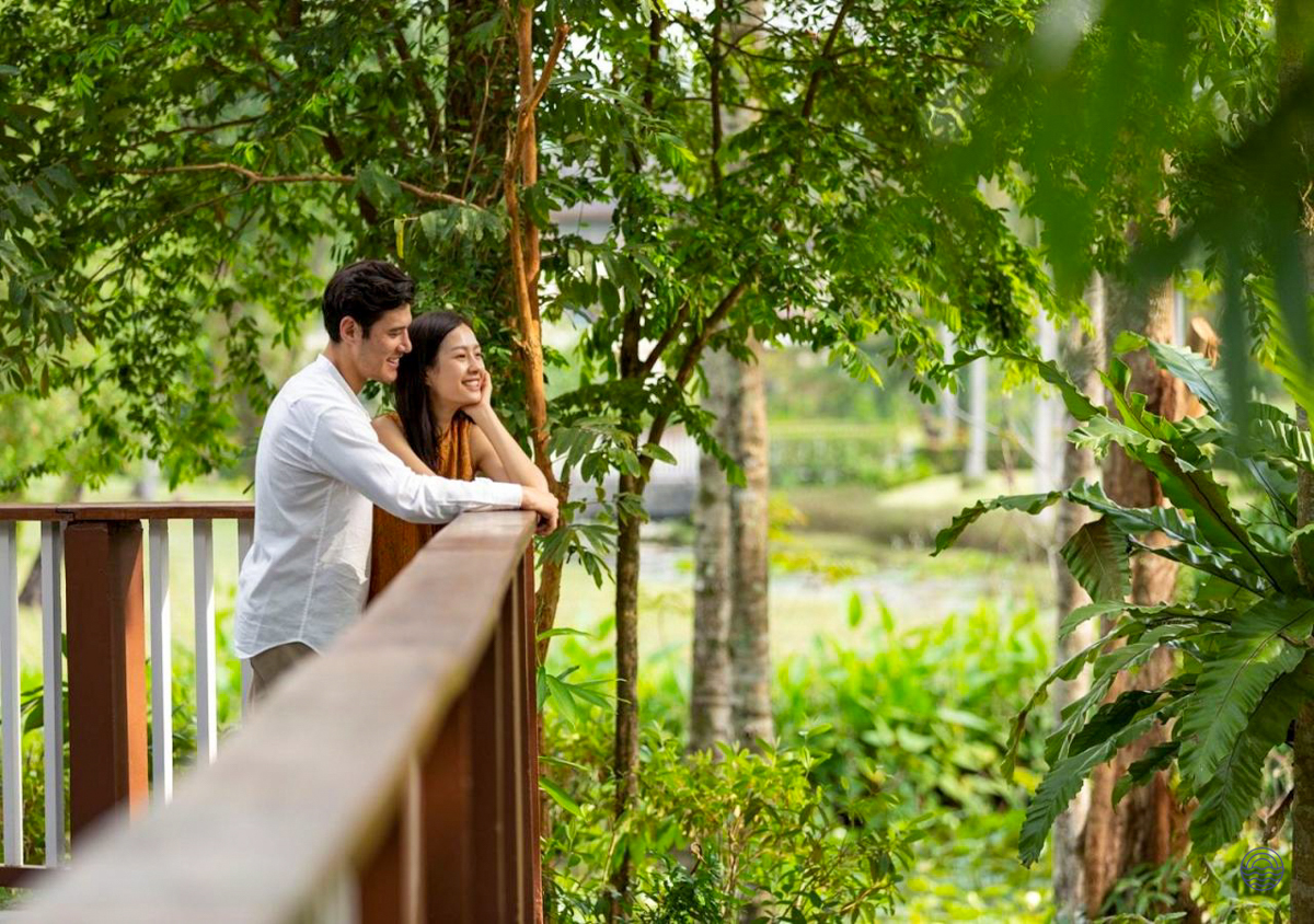 A happy couple enjoys the lush tropical scenery and calm waters from a balcony in Krabi.
