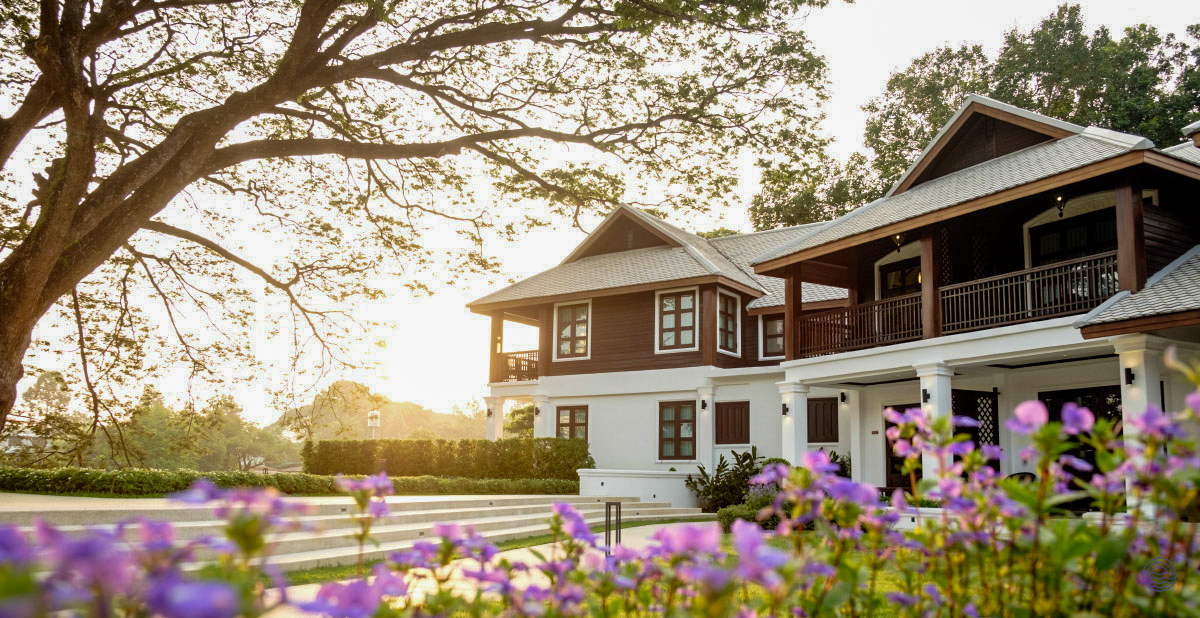 Serene traditional Thai-style resort in Chiang Mai, bathed in warm sunset light with purple flowers.