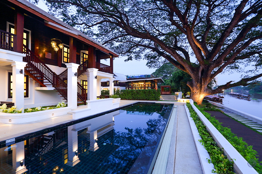 A stunning historical resort in Chiang Mai, with a beautiful pool, majestic tree, and serene river views.