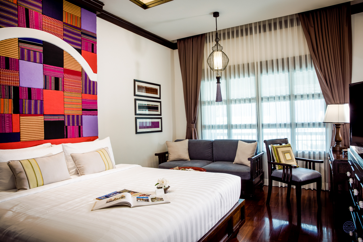 Luxurious hotel room in Chiang Mai with a comfortable bed, sofa, and elegant Thai decor.