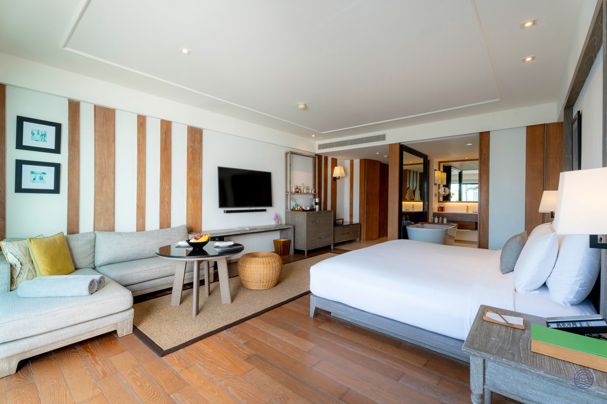 A luxurious resort room in Chiang Mai with a king bed, comfortable sofa, and open-plan bathroom.