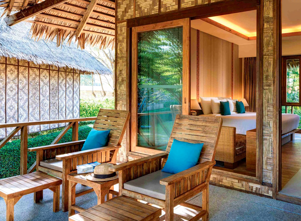 A luxurious tropical resort room in Koh Phi Phi with a private patio and comfortable lounge chairs.