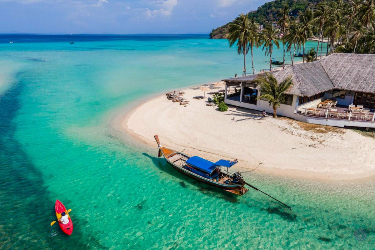 A longtail boat and kayak on the crystal-clear turquoise waters of a stunning Koh Phi Phi beach.