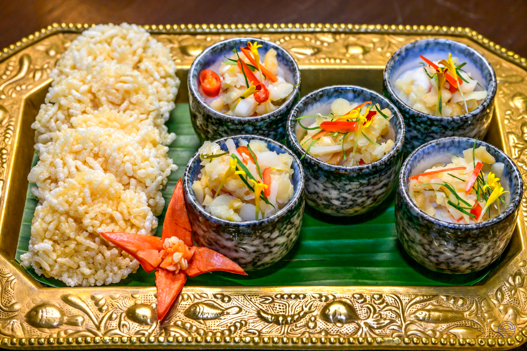 An authentic Thai welcome dinner with crispy rice cakes and small bowls of appetizers on a golden tray.