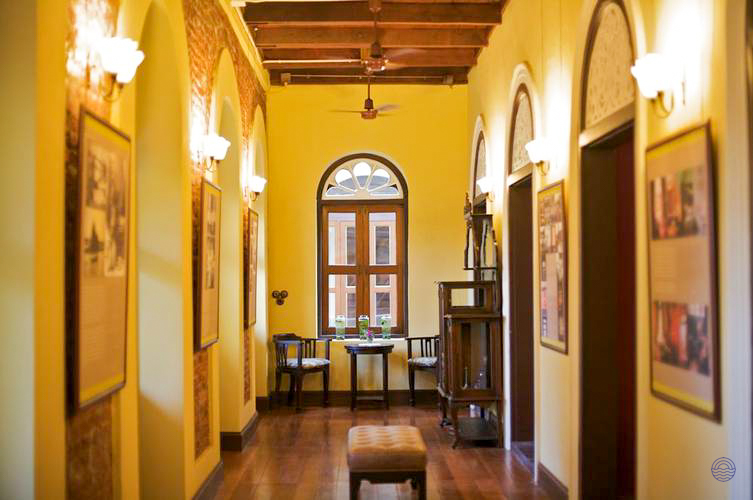 An elegant hallway with yellow walls, wooden floors, and traditional decor in a Bangkok hotel.