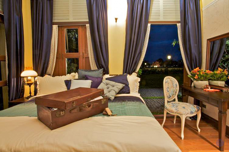 An inviting hotel room in Bangkok with a comfortable bed and a vintage suitcase ready for unpacking.