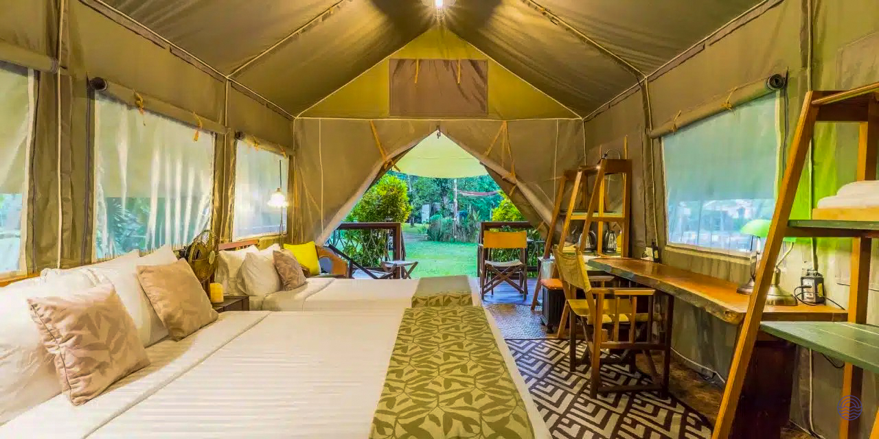 Inviting glamping tent accommodation in Kanchanaburi, Thailand, with comfortable beds and a lovely view of nature.