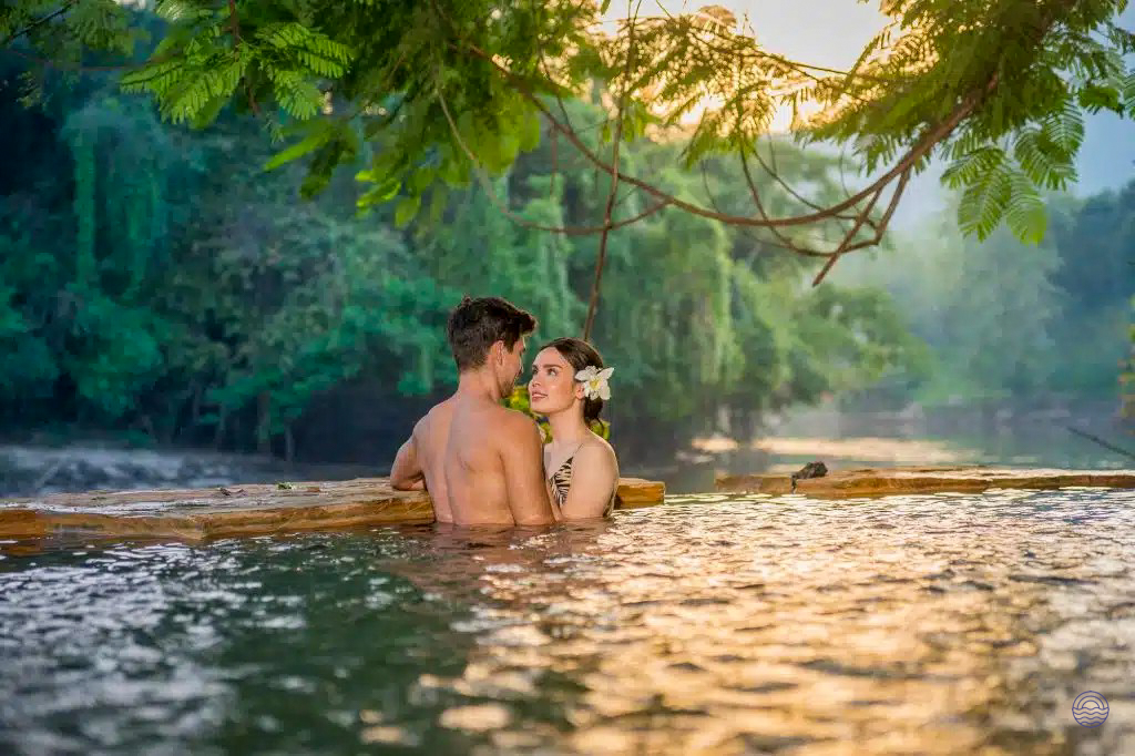 A romantic couple enjoys a peaceful moment in a natural pool in Kanchanaburi, Thailand.