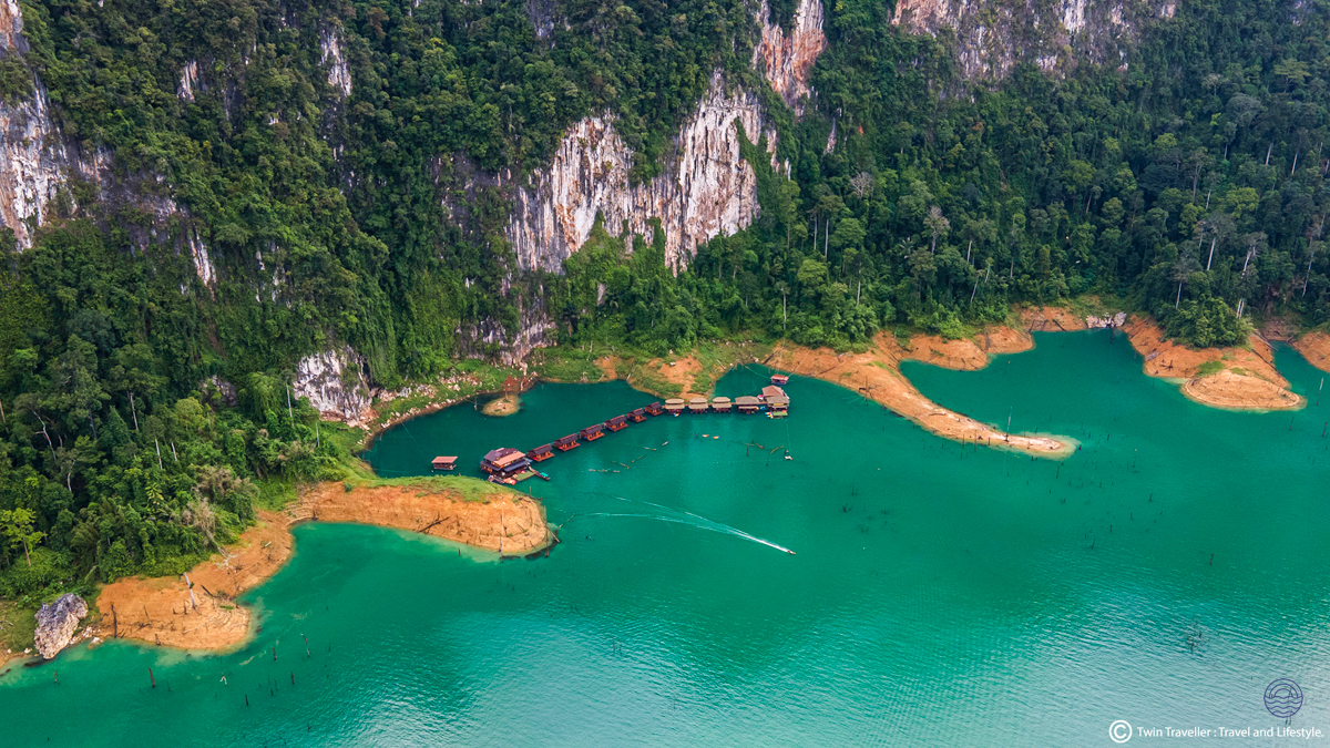 Floating bungalows nestled in a turquoise lake surrounded by dramatic jungle-covered limestone cliffs in Khao Sok.