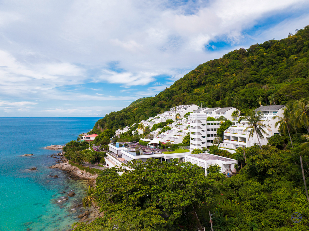 The Nai Harn resort's white buildings cascade down a lush green hillside to the turquoise sea in Phuket.